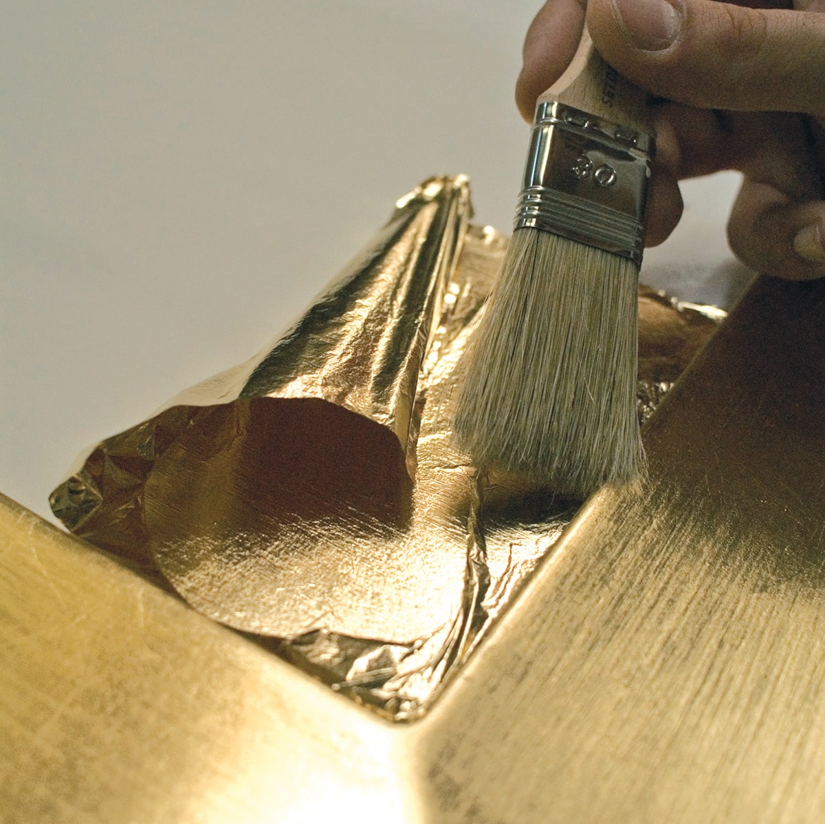 Finitura con foglia in oro su anta in legno